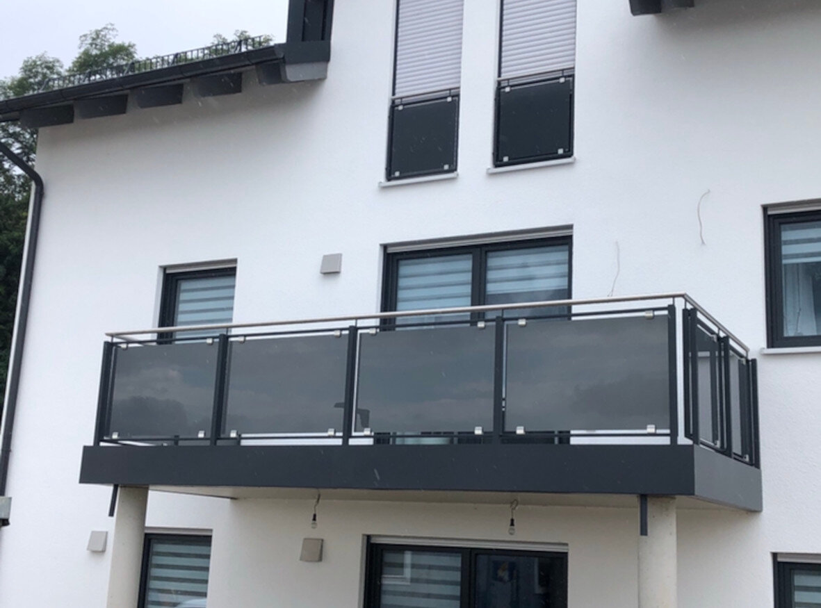 schwarzer Glasbalkon an weißem Haus
